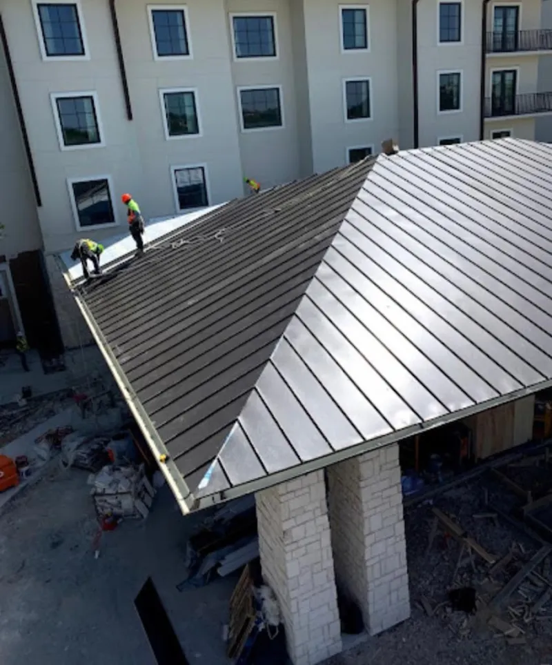 Crew installing standing seam metal roof panels on a commercial project in Glastonbury